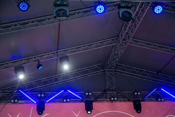Stage lights and rotating heads hang above the stage colored light