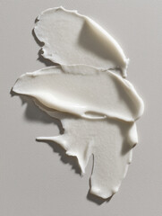 White smear of skincare cream on a soft gray background. Clean beauty product texture in macro style