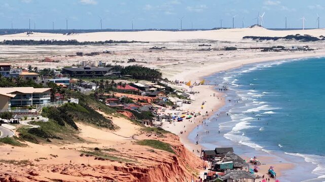 Canoa Quebrada beach, with wind turbines in the background. The red cliffs and sand dunes of Canoa Quebrada are what make this beach town famous. Brazil.