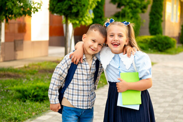 back to school. A girl and a boy, schoolchildren go to school in the first grade by the hand, a brother and sister with briefcases joyfully go to the ruler