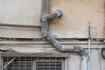 Plumbing installation includes water pipes and a sewerage system fixed to an old  building’s exterior wall in Israel