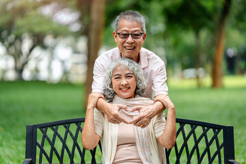 Joyful elderly couple showing affection mature adults forming heart shape hands smiling happy together beautiful green park outdoor