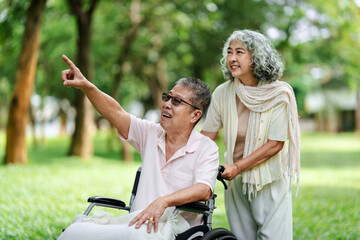 Elderly couple happy outdoor park scene senior man points woman assists companionably