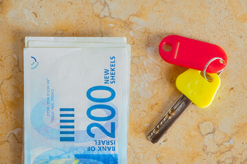 Cash money indicates rent payment or real estate purchase processes. key of a house and Israel new shekel banknotes Cash money