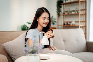 Woman relaxing with aromatherapy diffuser essential oils promoting longevity lifestyle at home living room for wellness health