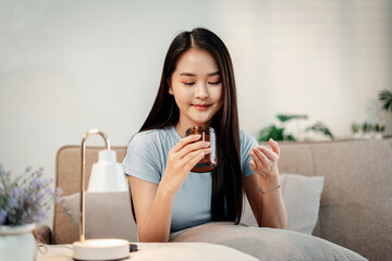 Asian woman preparing daily vitamins for health and longevity wellness routine promoting balanced lifestyle at home