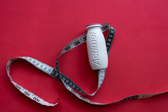 Warsaw, Poland, 07 27 2025:  close-up of a jar of Actimel yogurt next to a measuring tape. abstraction on the topic of proper nutrition and weight loss, the fight against excess weight and obesity