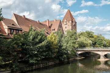 View of the tower Schuldturm in the German city Nuremberg with the river Pegnitz in the foreground.