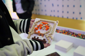 Obraz premium Close-up of children's hands holding a Lego art design made with wall art cubes at a play event
