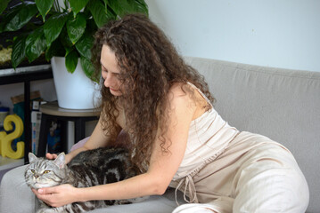 A Warm and Cozy Moment A Woman Sitting Comfortably with Her Adorable Cat on a Soft Sofa