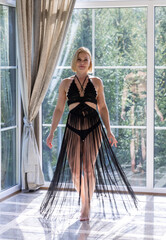 Elegant Woman in Black Fringe Dress by Sunlit Window