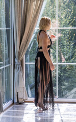 Elegant Woman in Black Fringe Dress by Sunlit Window