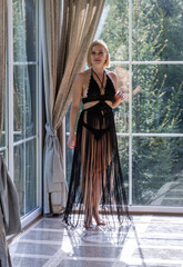 Elegant Woman in Black Fringe Dress by Sunlit Window