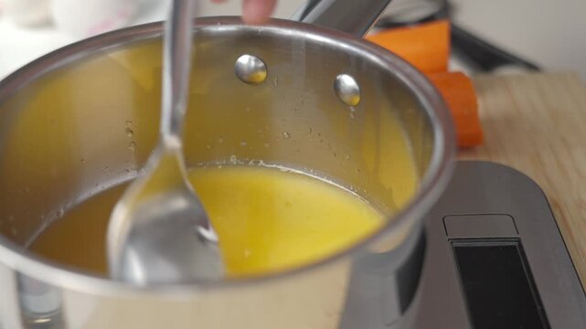 Sugar dissolving in juice inside saucepan on kitchen scale. Preparing syrup for homemade dessert
