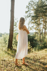 Woman enjoying nature in white dress at sunset in forest
