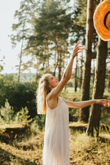Young woman throwing her straw hat in the air in a forest