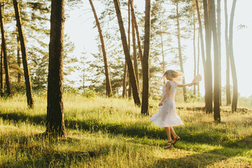 Happy woman dancing and twirling in sunny forest at sunset