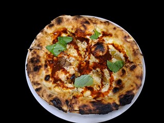 Close-up of Neapolitan pizza with mozzarella, tomato and basil on a black background