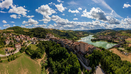 Panoramic aerial drone view of the medieval village of Sassocorvaro above the Mercatale dam, in the province of Pesaro Urbino, Marche, Italy. The village exudes peace, serenity, and ancient history.