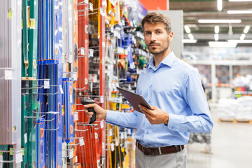 Warehouse worker scan goods in inventory in a hardware store and check stock product on digital...