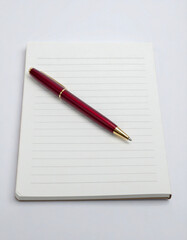 Naklejka premium Red ballpoint pen on a lined notebook