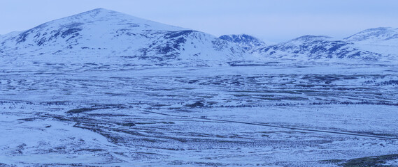 Winter landscape with road, valley and Snøhetta massif in Dovrefjell, Norway © Dreamnordno