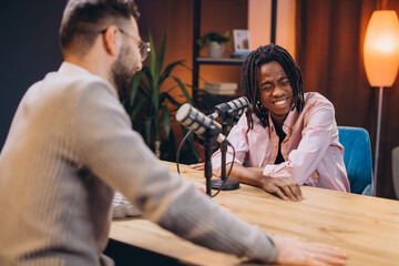 Two male podcasters are recording a podcast in a studio, using professional microphones and equipment