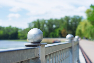 Close-up view of the bridge's metal railing and green trees under a bright sky.
