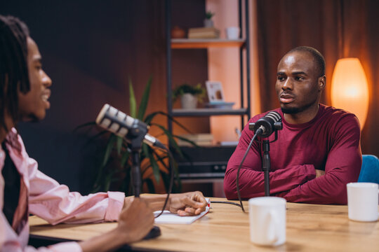 Two content creators recording audio for their podcast in a professional studio, engaging in conversation and sharing their thoughts with microphones