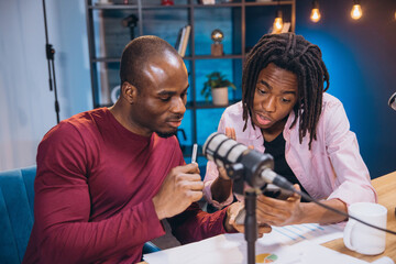 Two podcasters are recording their show, discussing and sharing ideas in a professional studio