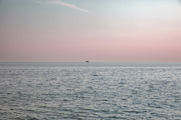Ship silhouette on calm sea at golden hour sunset