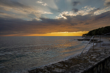 Golden sunset over calm ocean with pier and beach