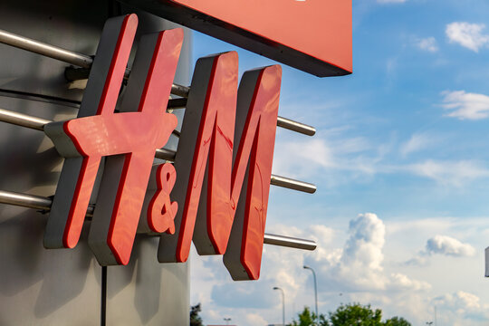 H&M logo sign on a modern metal structure, photographed outdoors with a blue sky background