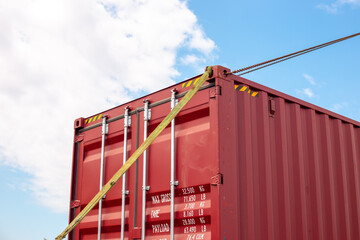 Close-up of a strap securing a corner of a metal shipping container. Cargo transportation and unloading