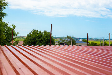 View of new corrugated roofing against clear sky and trees. Roof construction