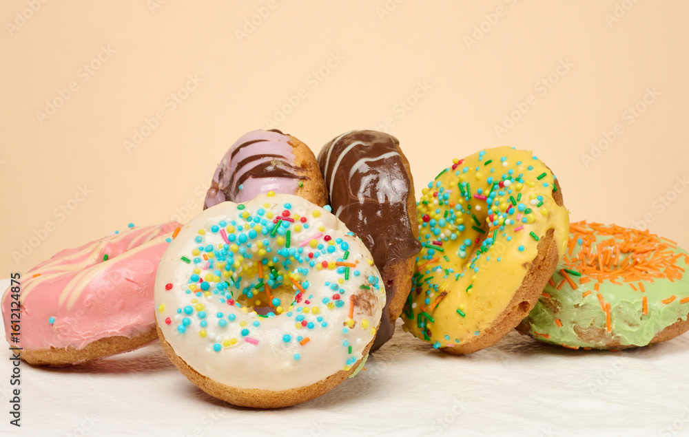 Poster stack of donuts with different toppings and glazes, beige background