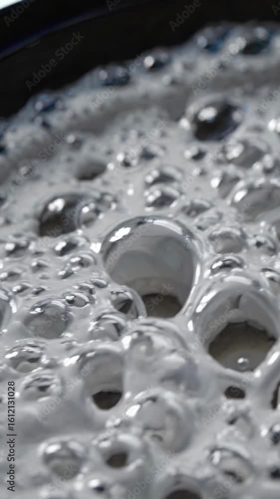 Poster close-up video of bubbling liquid surface, capturing abstract patterns. shot from a low angle, empha