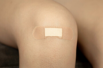 Adhesive bandage on a knee after a minor accident. First aid concept for a childhood scrape or...