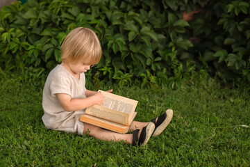 Young child reading a book outdoors on the grass