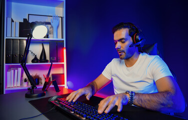 Serious face gaming streamer concentrating gaming players trying to pass at mission completed, using headset and mic for communicate others on streaming live at neon lighting studio room. Surmise.