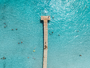 Aerial View of pier and swimming people in azure sea in Alcudia, Spain. Top drone view of wooden...