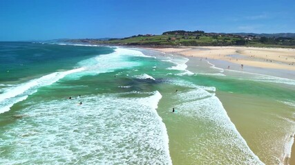 An aerial view showcases a picturesque beach featuring surfers riding the turquoise waters on a bright and sunny day - Powered by Adobe