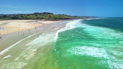 A breathtaking aerial view showcasing a vibrant beach filled with surfers, sunbathers, and shimmering clear blue water