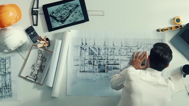 Top view of smart civil engineer drawing and measuring blueprint by using ruler. Aerial view of architect scatch building project plan at meeting table with equipment and safety helmet. Alimentation.