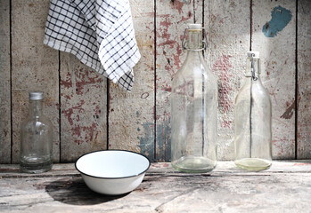 Rustic Kitchen Scene with Glass Bottles and Enamel Bowl