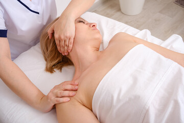 Girl lies on her back having massage from body therapist