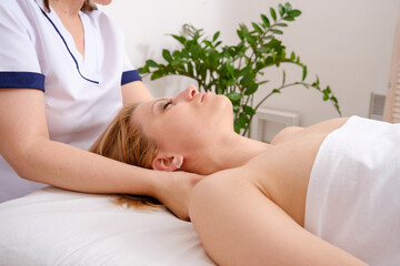 Girl lies on her back having massage from body therapist