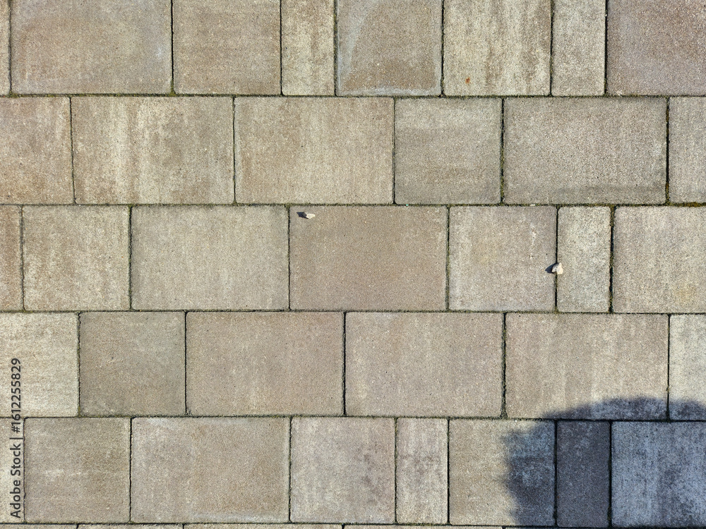 Poster close-up view of a textured concrete pavement surface with rectangular tiles arranged in a grid patt