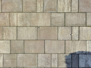 Close-up view of a textured concrete pavement surface with rectangular tiles arranged in a grid...
