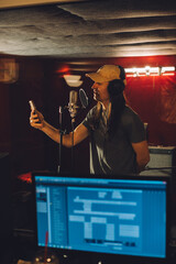 Singer recording song using smartphone in professional studio